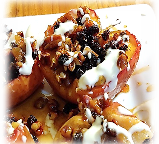 Baked apple covered in raisins, syrup, and creme fraiche, and pecans. The apple sits on a white plate atop a wooden surface.