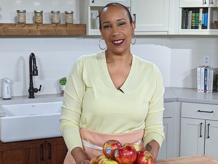 Chef Elle Simone standing in a kitchen with a bowl of Pazazz apples
